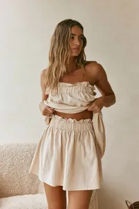 Summer French resort style linen-blend strapless crop top and ruffled mini skirt two-piece set.