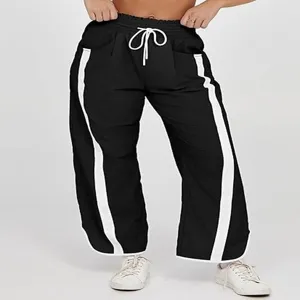 Details van zwarte wijde joggingbroek met contrasterende witte strepen en trekkoord.