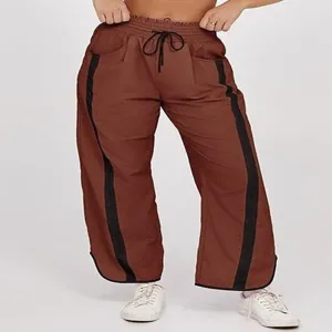 Gedetailleerd overzicht van casual bruine dames joggingbroek met zwarte zijstrepen.