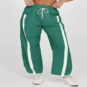 Gedetailleerd aanzicht van groene casual broek met witte zijstrepen en trekkoord in taille.