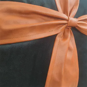 Black velvet sofa throw pillow close-up detail featuring a stylish brown leather bow.