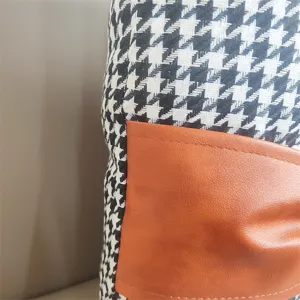 Houndstooth velvet cushion detail with orange leather patchwork for cozy sofa decor.