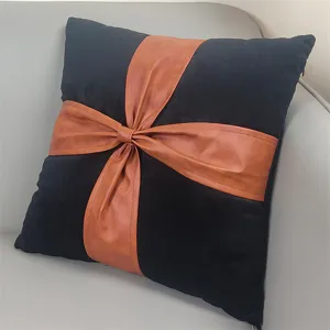 Black velvet pillow with brown leather bow accent, stylish cushion for home sofa decor.