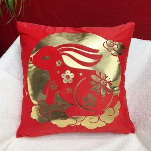 Detailed close-up shot of the red plush throw pillow featuring festive gold rabbit and cloud decor.