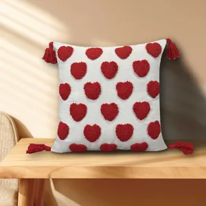 White square throw pillow with red tufted hearts and corner tassels for sofa home decor.