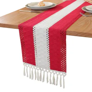 Red and white crocheted table runner with tassels for holiday party dining table decor.
