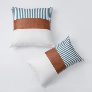 Detail shot of decorative pillow cover featuring blue stripes, brown leather, and white fabric.