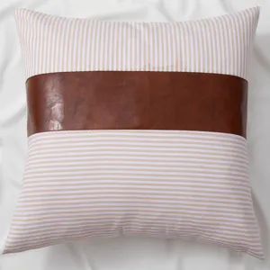 Detailed close-up of the striped pillow featuring a stylish brown leather center patch design.