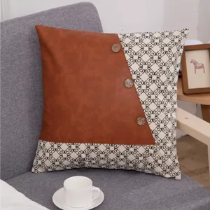 Detail view of patchwork leather pillow cover with geometric fabric and wooden button decor.