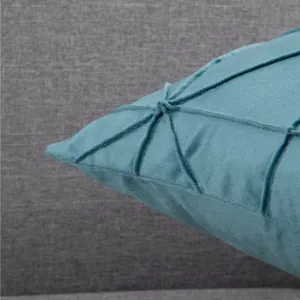 Nahaufnahme des türkisfarbenen Samtkissens mit stilvollem Falten-Gitterdesign und weicher Textur.