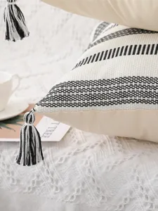 Gros plan détaillé du coussin style nordique en coton tissé rayé noir et blanc avec pompons.