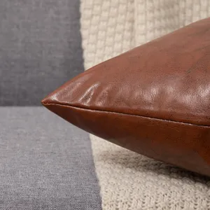 Detail shot of brown leather pillowcase, smooth texture, sofa cushion cover decor.
