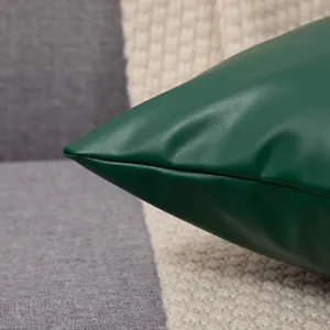 Close up of dark green leather pillow cover detail showing fine texture and neat stitching.