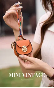 Mini borsa a sella arancione ciondolo portachiavi con nastro di lusso e dettagli dorati.