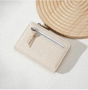 Detailed view of women's short woven wallet, beige zipper coin purse with elegant texture.