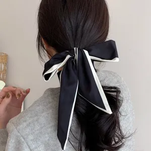 Close-up detail of the elegant black and white bow hair tie with long ribbon tail for ponytail.