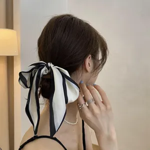 Detail shot of a chic black and white striped bow hair scrunchie with long streamers for women.
