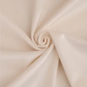 Gros plan sur la texture de tissu velours beige doux, montrant une matière lisse.