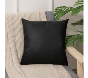 Vista detallada de un cojín de piel sintética negra con textura suave para hogar.