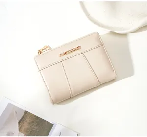 Close-up detail of beige PU short wallet, showing metallic branding and fine stitching.