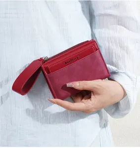 Close-up detail of women's short color-block wallet with zipper and wrist strap.