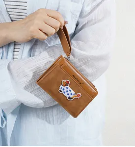 Detailed view of the brown leather short coin purse with a cute embroidered puppy patch and wrist strap.