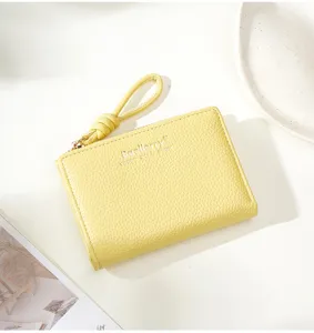 Vue détaillée d'un petit portefeuille femme jaune en cuir synthétique avec fermeture éclair.