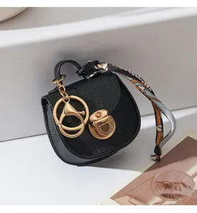 Dettaglio portachiavi mini borsa sella portamonete in pelle PU nera con accessori dorati.