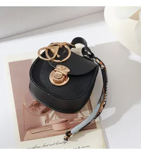 Primo piano dettagliato di un elegante portachiavi a borsa a sella nera con dettagli dorati.