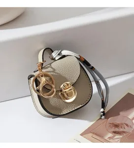 Dettaglio del mini ciondolo borsa sella in pelle con dettagli dorati e sciarpa twilly.