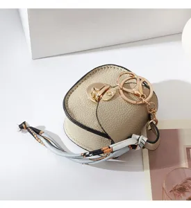Mini borsa portachiavi in ecopelle con chiusura dorata e charm in nastro di seta chic.