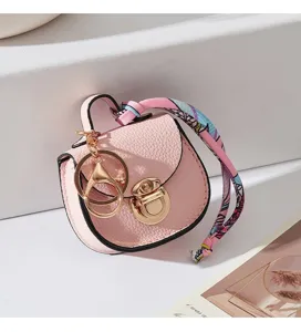 Primo piano di un grazioso ciondolo a forma di borsa a sella rosa con dettagli dorati.