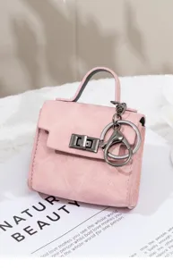 Nahaufnahme der rosa Mini-Handtasche als Schlüsselanhänger mit feiner Textur und Metallschloss.