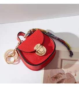 Elegante portachiavi mini borsa a sella rossa con dettagli dorati e nastro colorato.