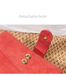 Rotes Wildleder Portemonnaie Detail mit goldenen Druckknöpfen und feinen Nähten verarbeitet.