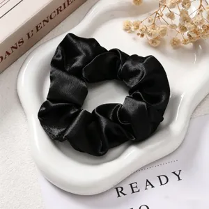Elegante zwarte satijnen haarelastiek scrunchie, klassiek Franse vintage haaraccessoire detail.