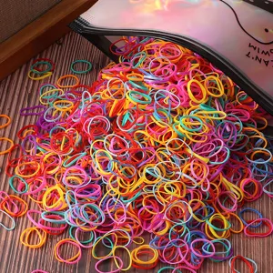 Detailed view of colorful disposable hair rubber bands for girls, scattered on wooden table.