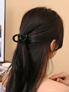 Detail shot of a sleek black hair claw clip styling dark hair, minimalist design accessory.