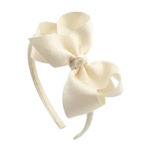 Close-up detail shot of the elegant off-white grosgrain ribbon bow headband for cute children.