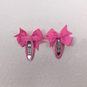 Pink bow hair clip detail shot, full-wrapped fabric design, cute kids hair accessories closeup.