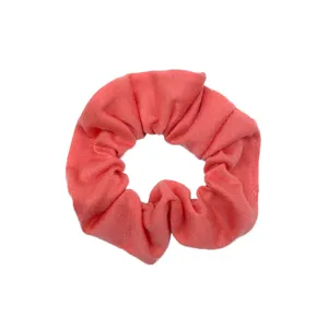 Primo piano di un morbido scrunchie in tessuto rosa corallo, che mostra una bella struttura.