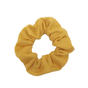 Vista dettagliata del morbido scrunchie in cotone giallo, ideale per acconciature casual.