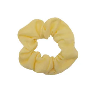 Primo piano di uno scrunchie in tessuto giallo, morbido ed elastico per acconciature.
