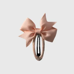 Pink bow hair clip detail showing delicate ribbon texture and secure metal clasp design.