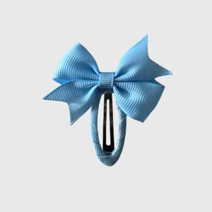 Close-up detail of light blue grosgrain ribbon bow hair clip with secure metal snap design.