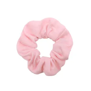 Dettaglio di scrunchie in tessuto rosa, texture morbida e semplice accessorio per capelli.