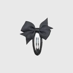 Detail close-up of a black grosgrain ribbon bow hair clip, showing wrapped metal clip structure.
