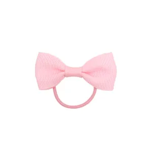Primo piano dettagliato del elastico capelli con fiocco in grosgrain rosa per bambina.