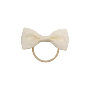 Primo piano dettagliato dell'elastico per capelli con fiocco in nastro beige strutturato.