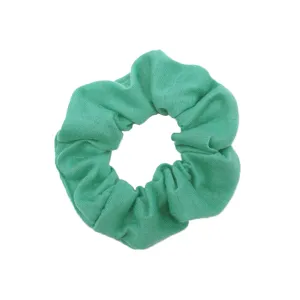 Primo piano dettaglio di un semplice scrunchie per capelli in tessuto verde, morbido.